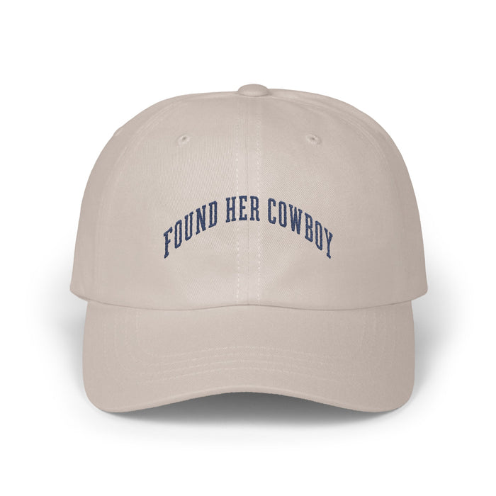 Beige baseball cap with curved dark blue embroidered text reading FOUND HER COWBOY centered on the front panels.
