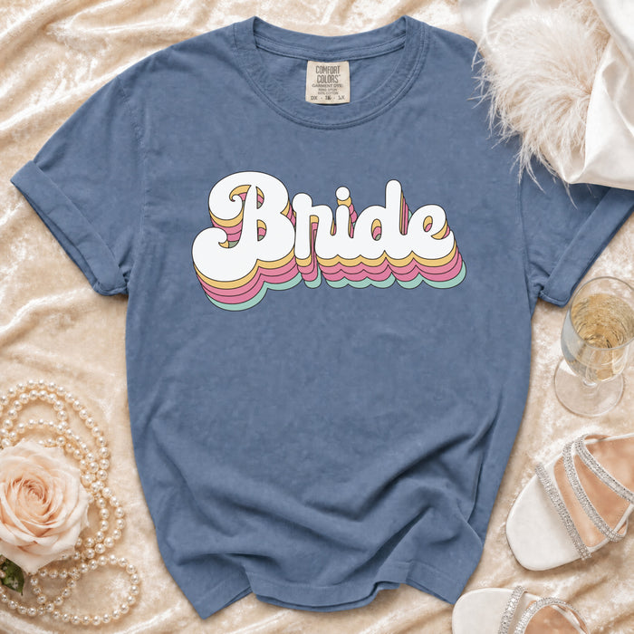 Blue t-shirt with "Bride" in layered retro font and wedding accessories.