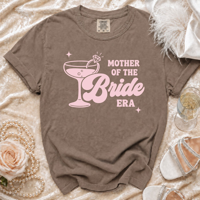 Brown t-shirt with pink "Mother of the Bride Era" text and cocktail graphic.