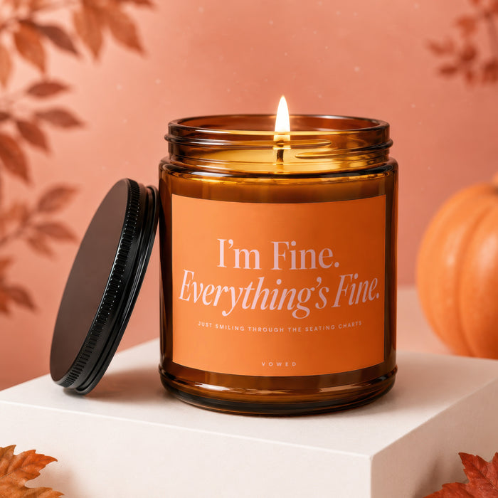 Lit amber glass candle with text "I'm Fine. Everything's Fine." and a pumpkin.