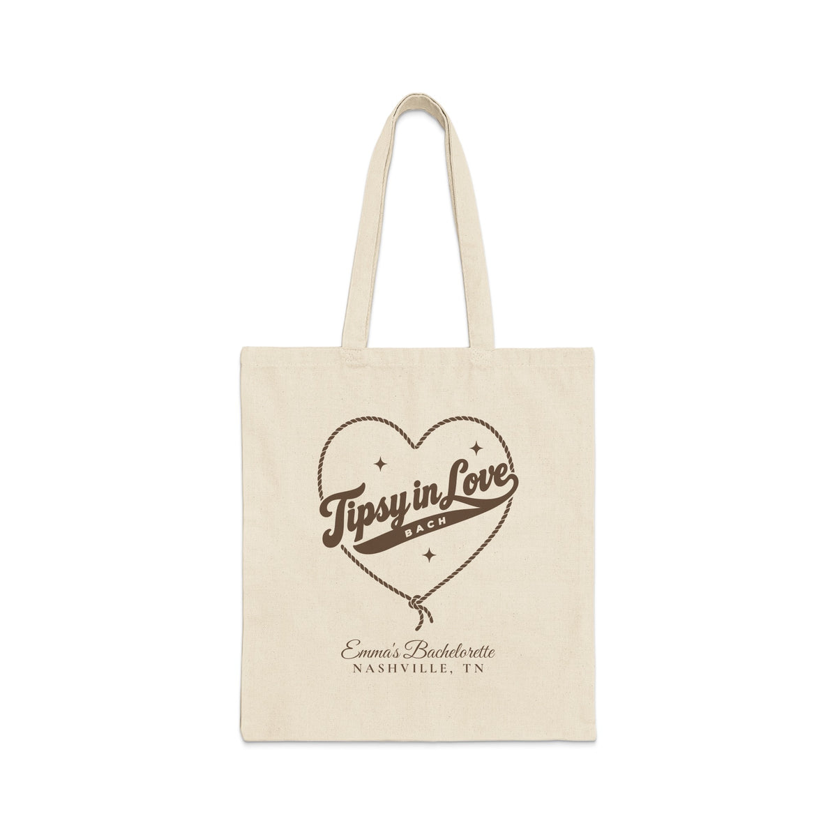 A plain canvas tote bag featuring brown print with a rope-outlined heart, stars, and text reading Tipsy in Love Bach.