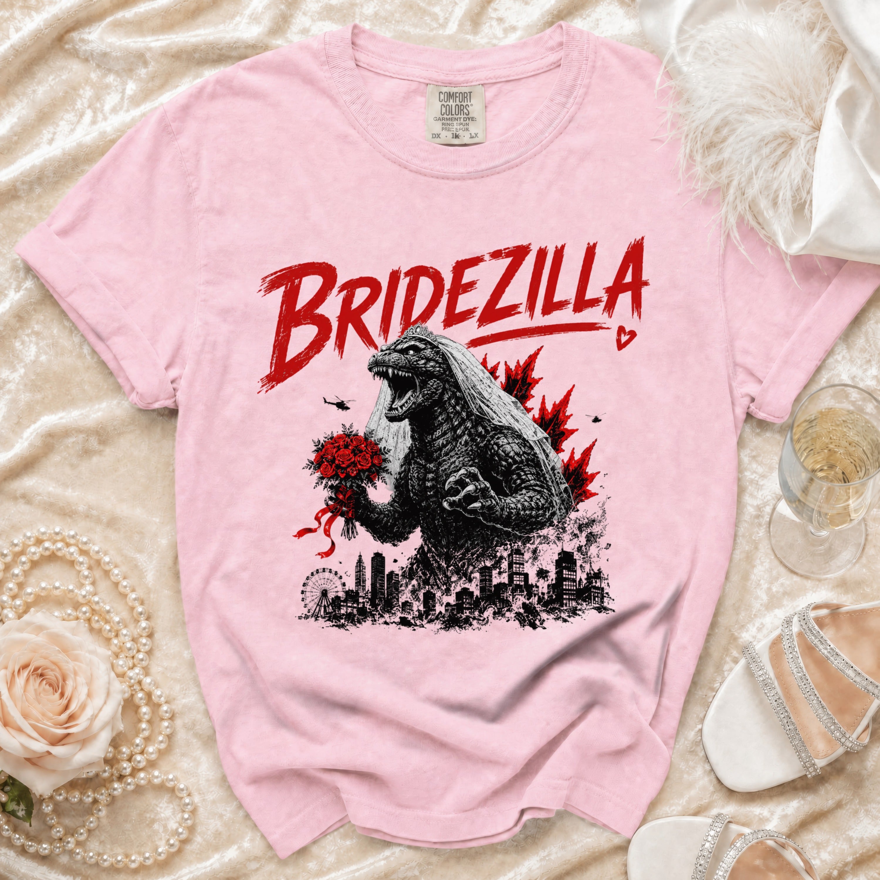 Pink t-shirt with "BRIDEZILLA" text and an illustration of Godzilla in a wedding veil holding flowers.