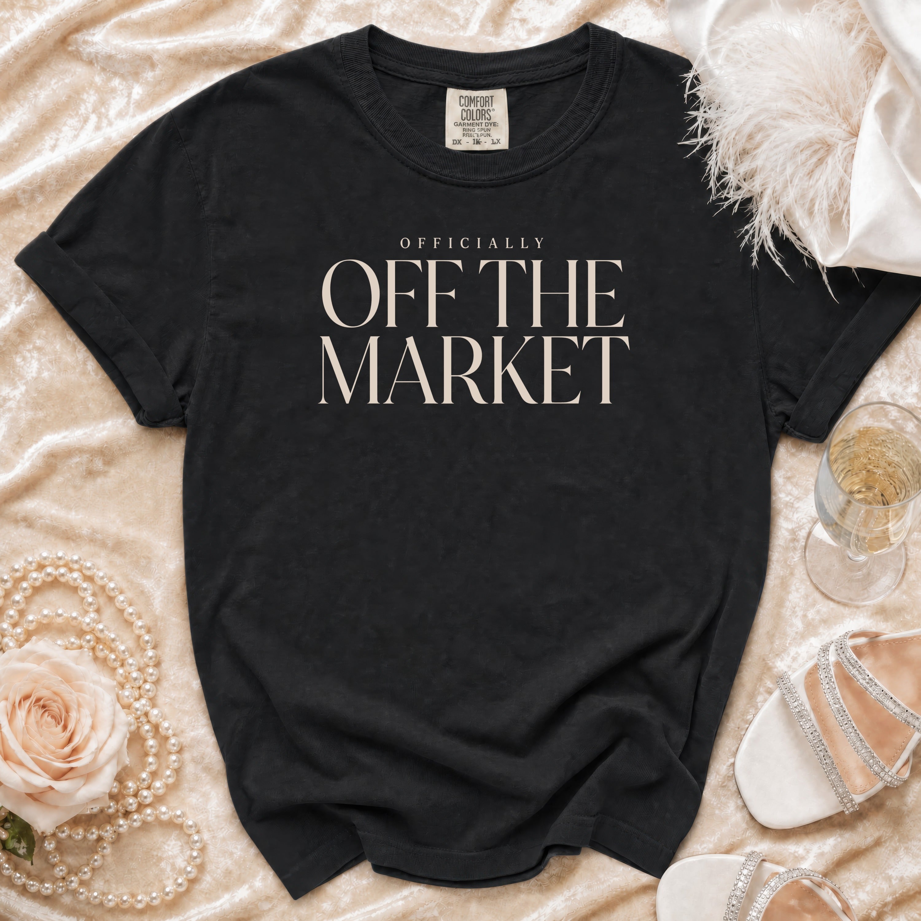Black t-shirt with "OFFICIALLY OFF THE MARKET" text, draped on fabric.