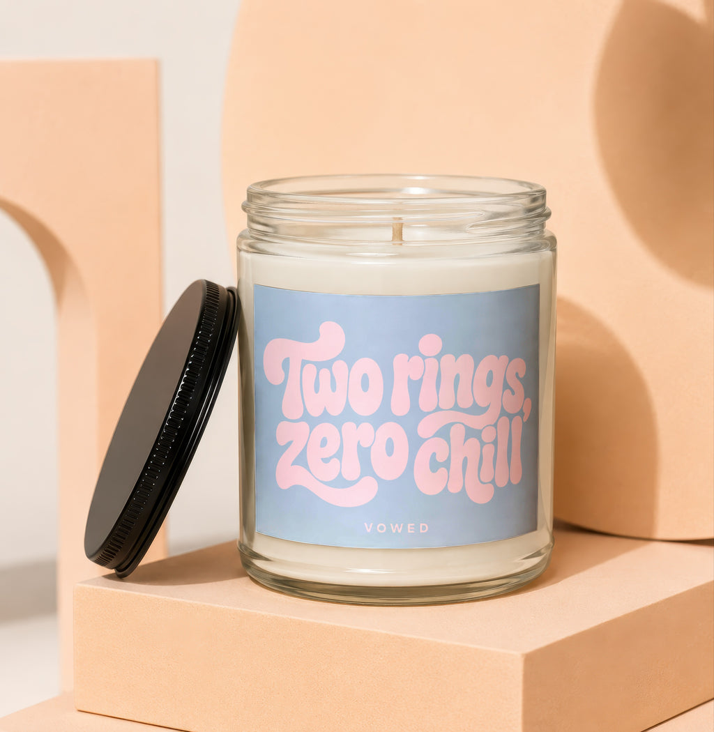 Glass candle with "Two rings, zero chill" text on a blue label.