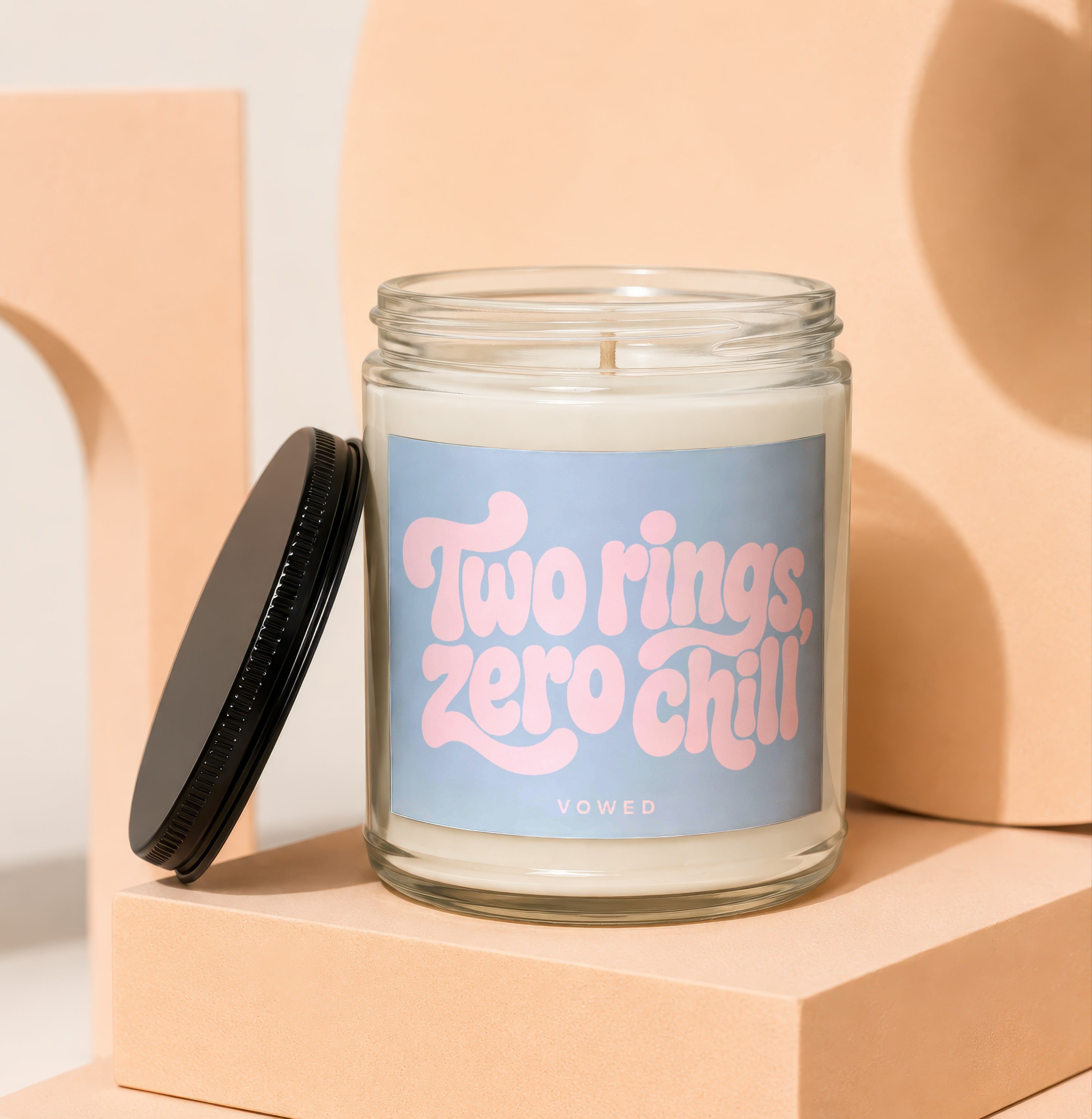 Glass candle with "Two rings, zero chill" text on a blue label.