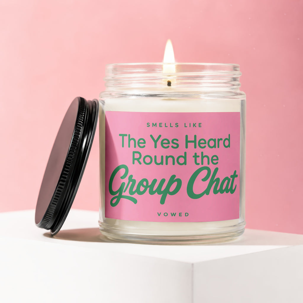 Candle with pink label reading "Smells Like The Yes Heard Round the Group Chat Vowed".