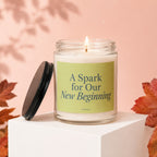 Lit candle in glass jar with "A Spark for Our New Beginning" text, with lid off.