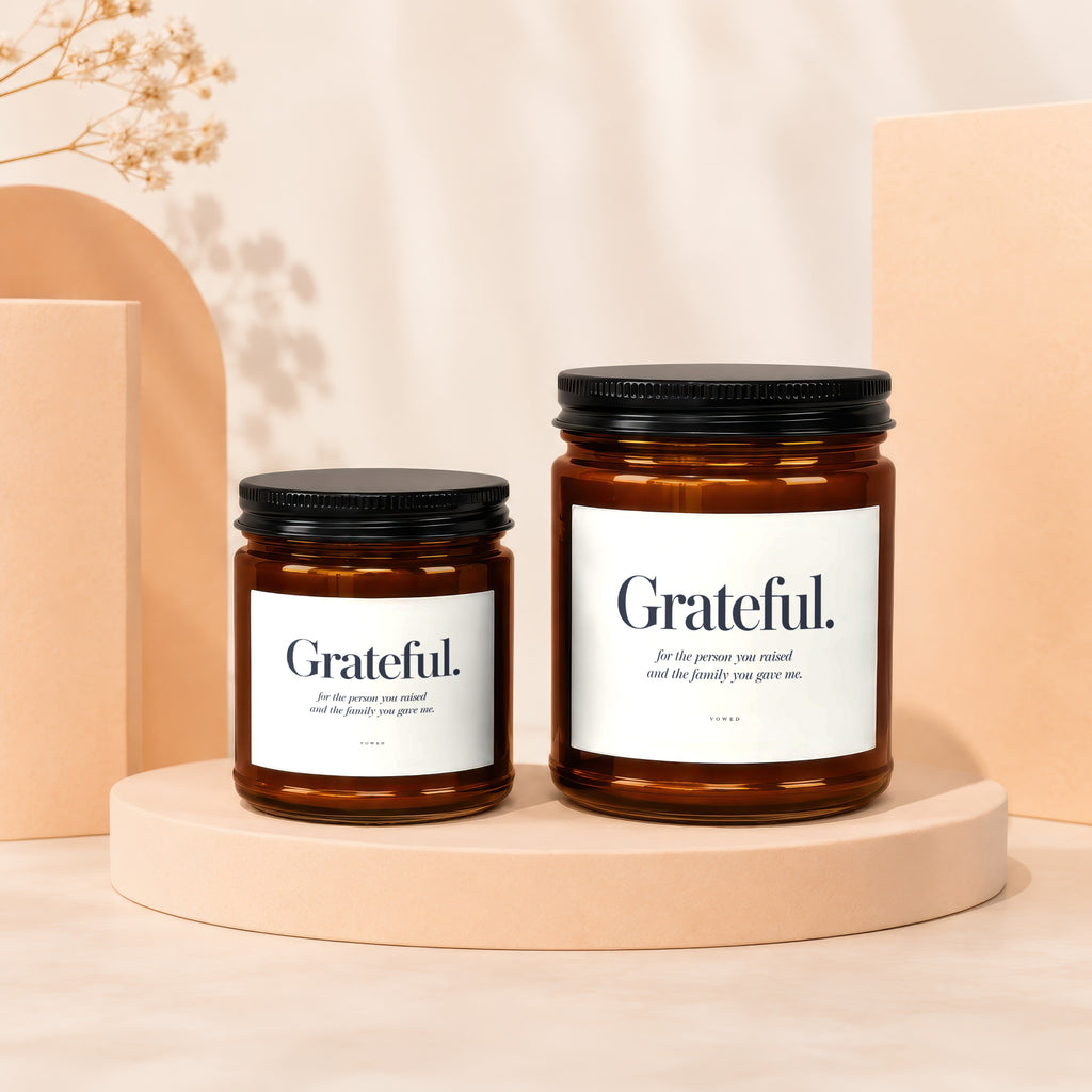 Two amber glass candles with black lids, both labeled "Grateful."