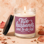 Glass candle with burning wick and label reading "Two husbands, one to-do list."