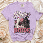 Lavender Comfort Colors shirt featuring a ghost and haunted house graphic with "Mother of the Bride" text.