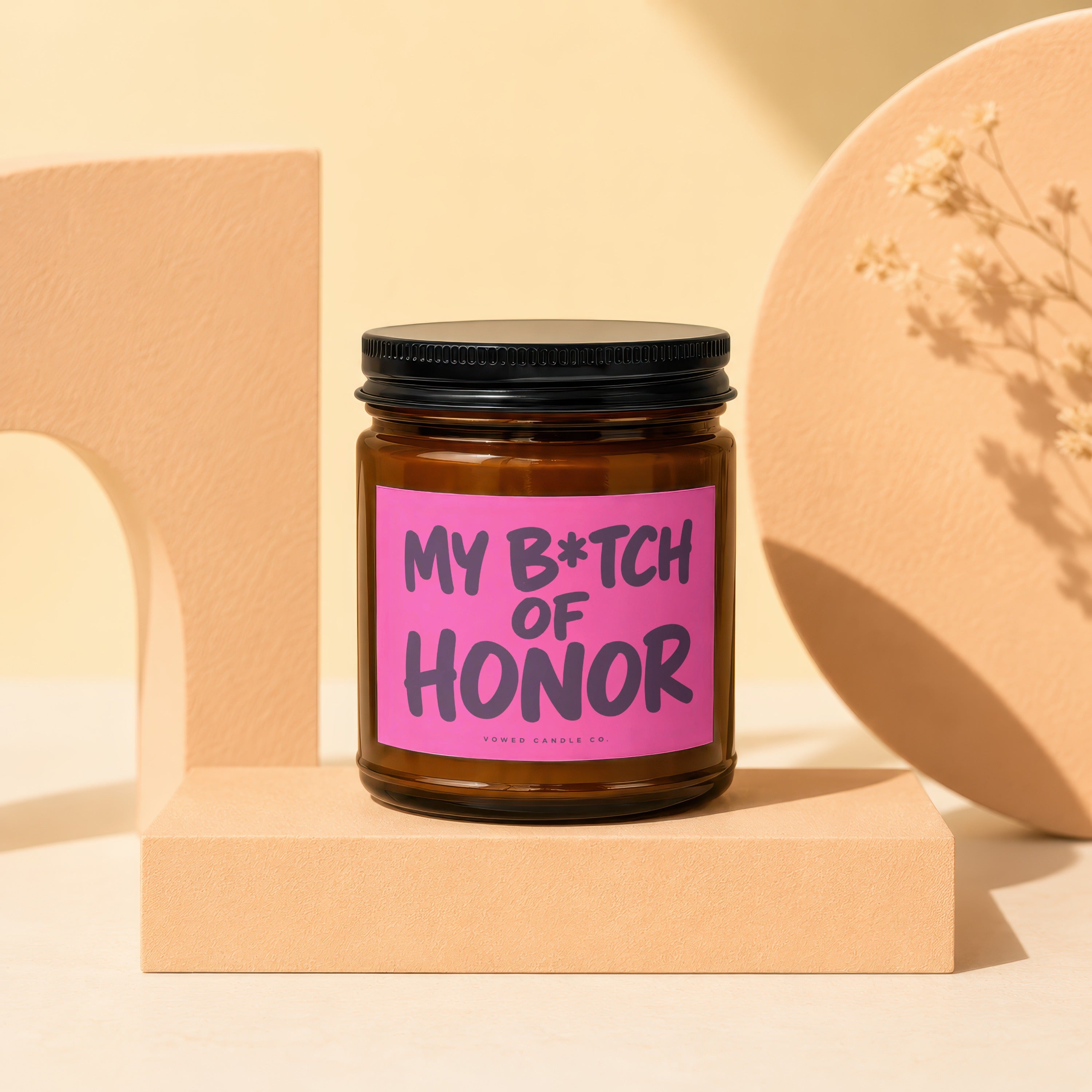 Brown glass candle with pink label reading "MY B*TCH OF HONOR", from Vowed Candle Co.