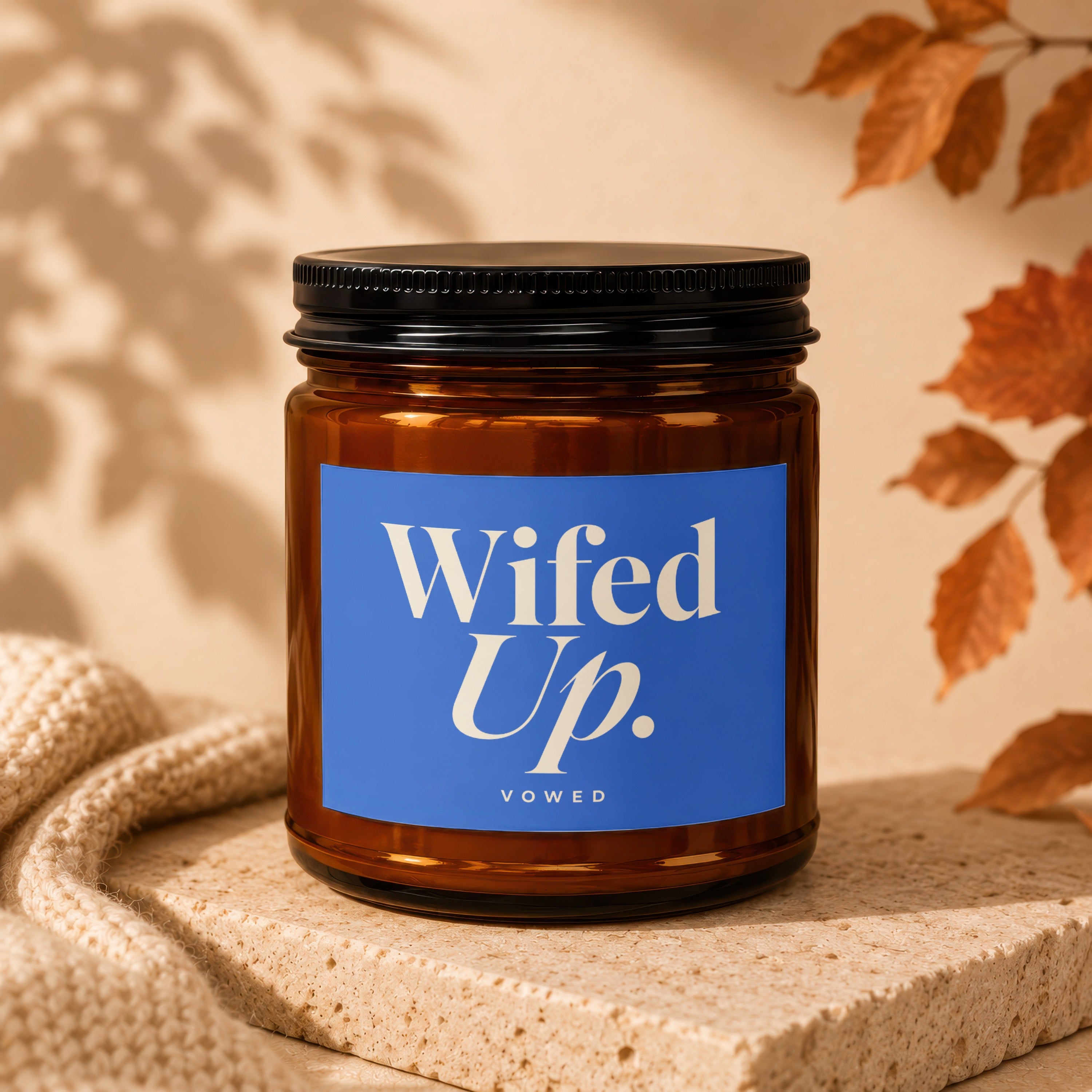 Amber glass candle with a blue label reading "Wifed Up. Vowed."