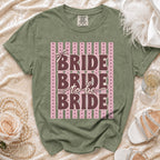 Green t-shirt with "BRIDE to be BRIDE" text on pink and green striped background.