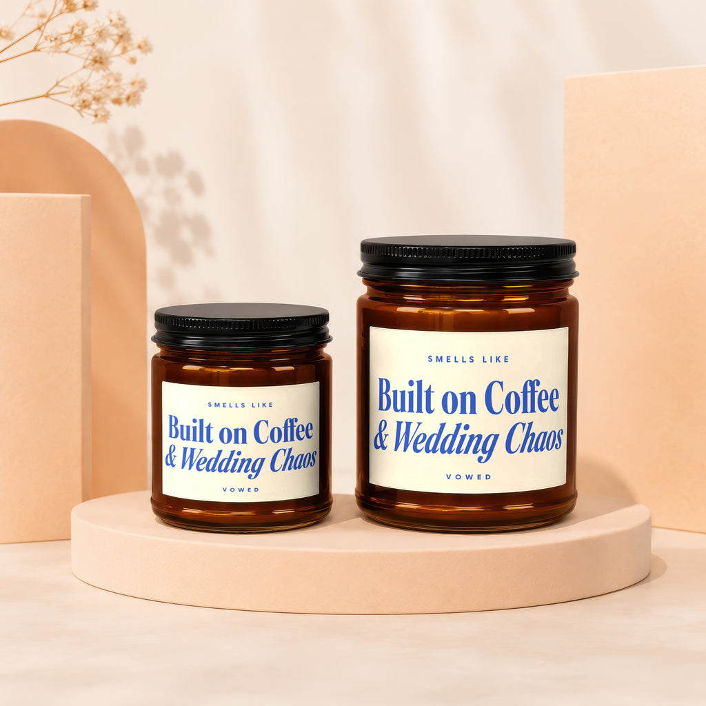 Two amber glass candles with black lids feature labels reading "Built on Coffee & Wedding Chaos."