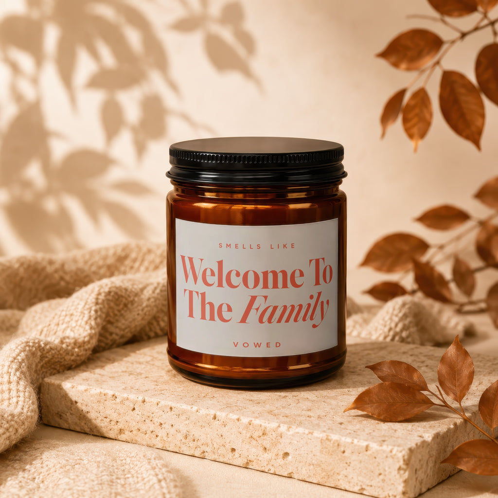 Amber candle with black lid labeled "Welcome To The Family".