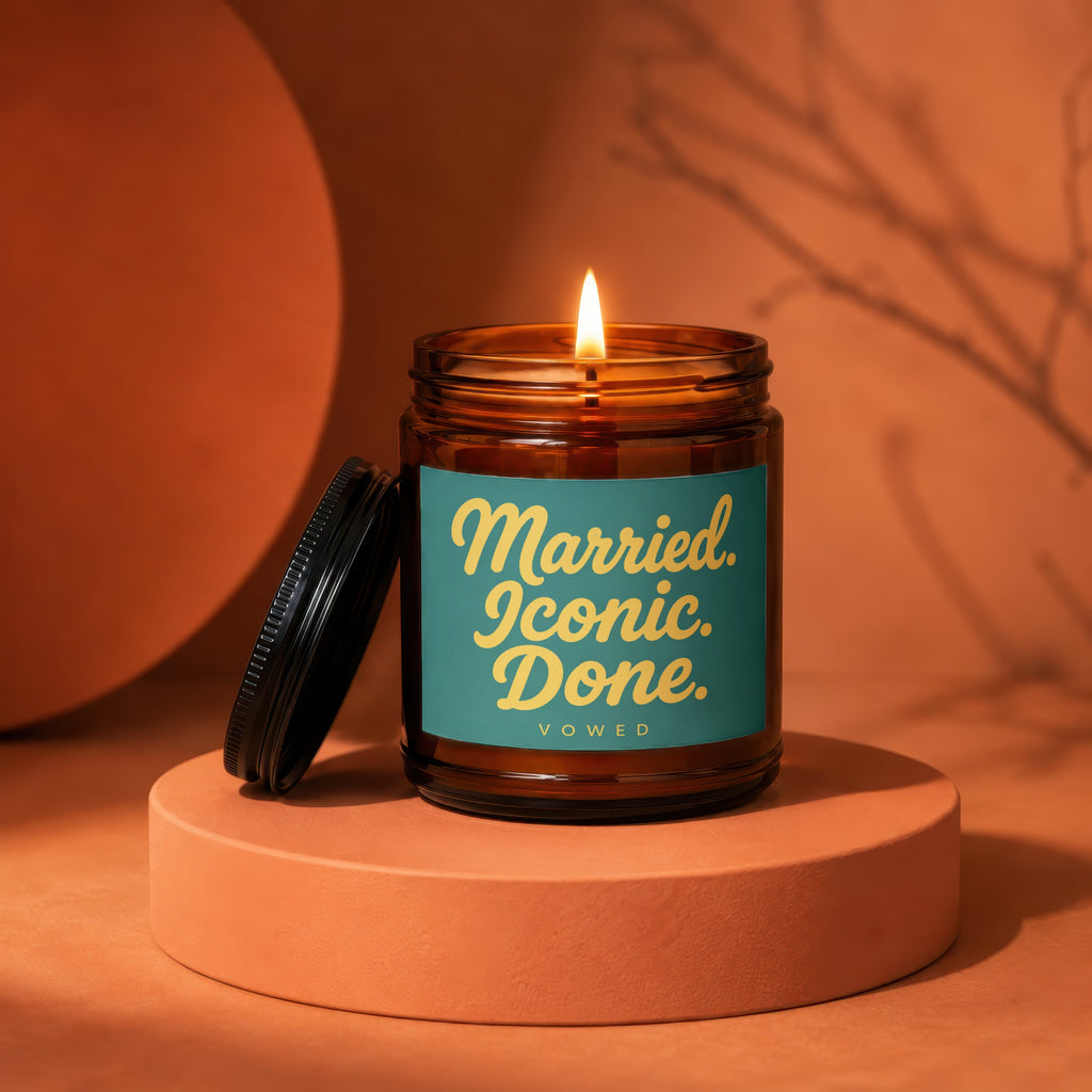 Amber jar candle with a lit wick and label reading "Married. Iconic. Done. VOWED."