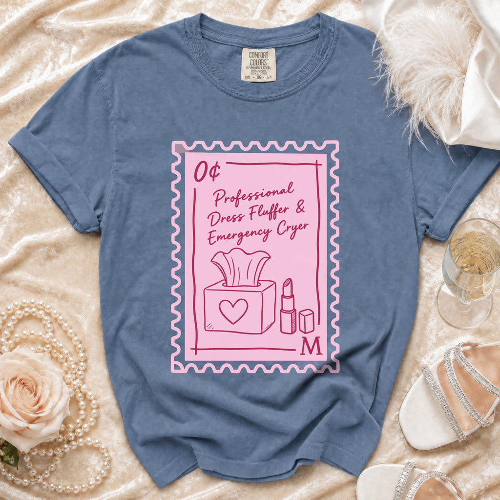 Blue t-shirt with a pink stamp graphic reading "Professional Dress Fluffer & Emergency Cryer".