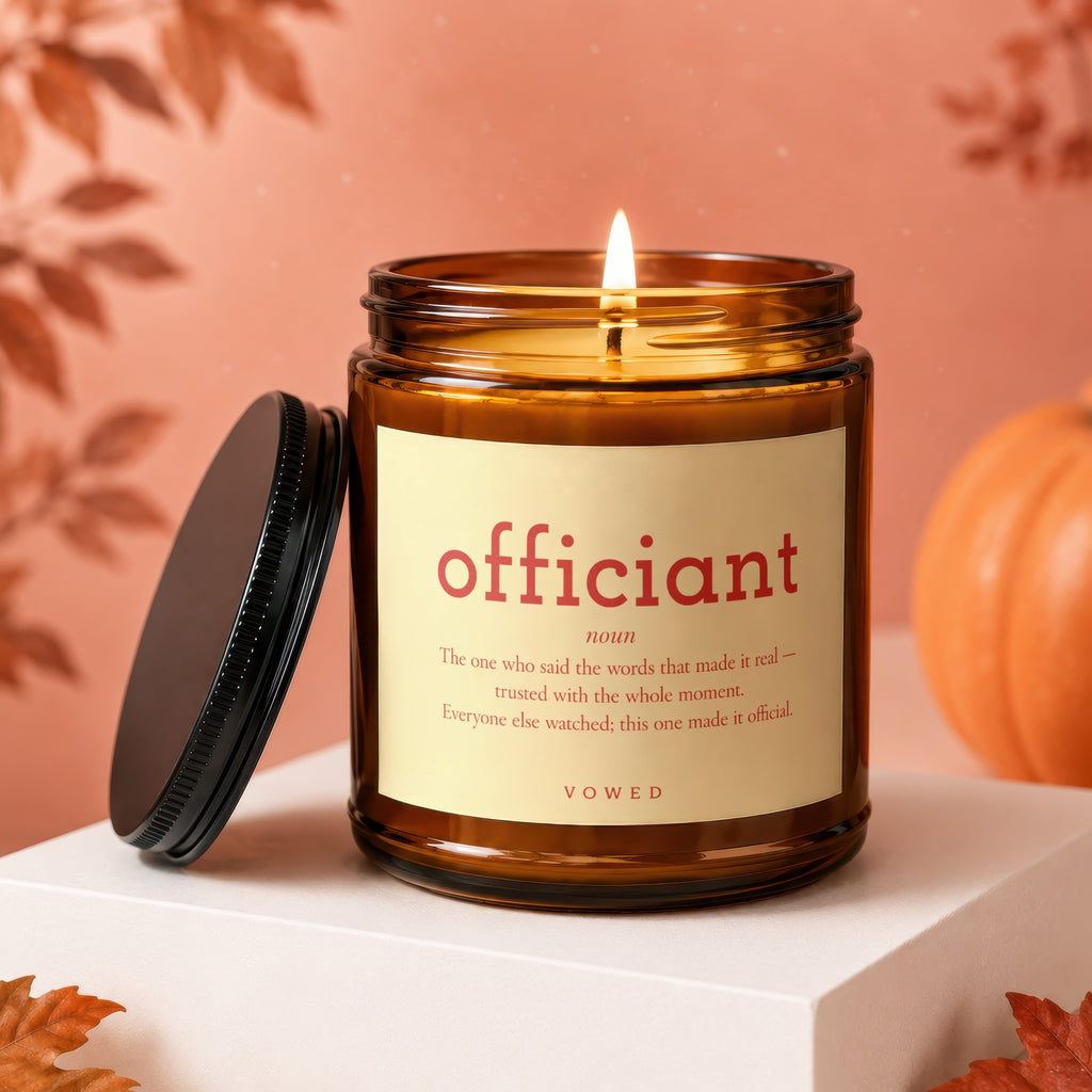 Amber jar candle with "officiant" definition and autumnal decor.