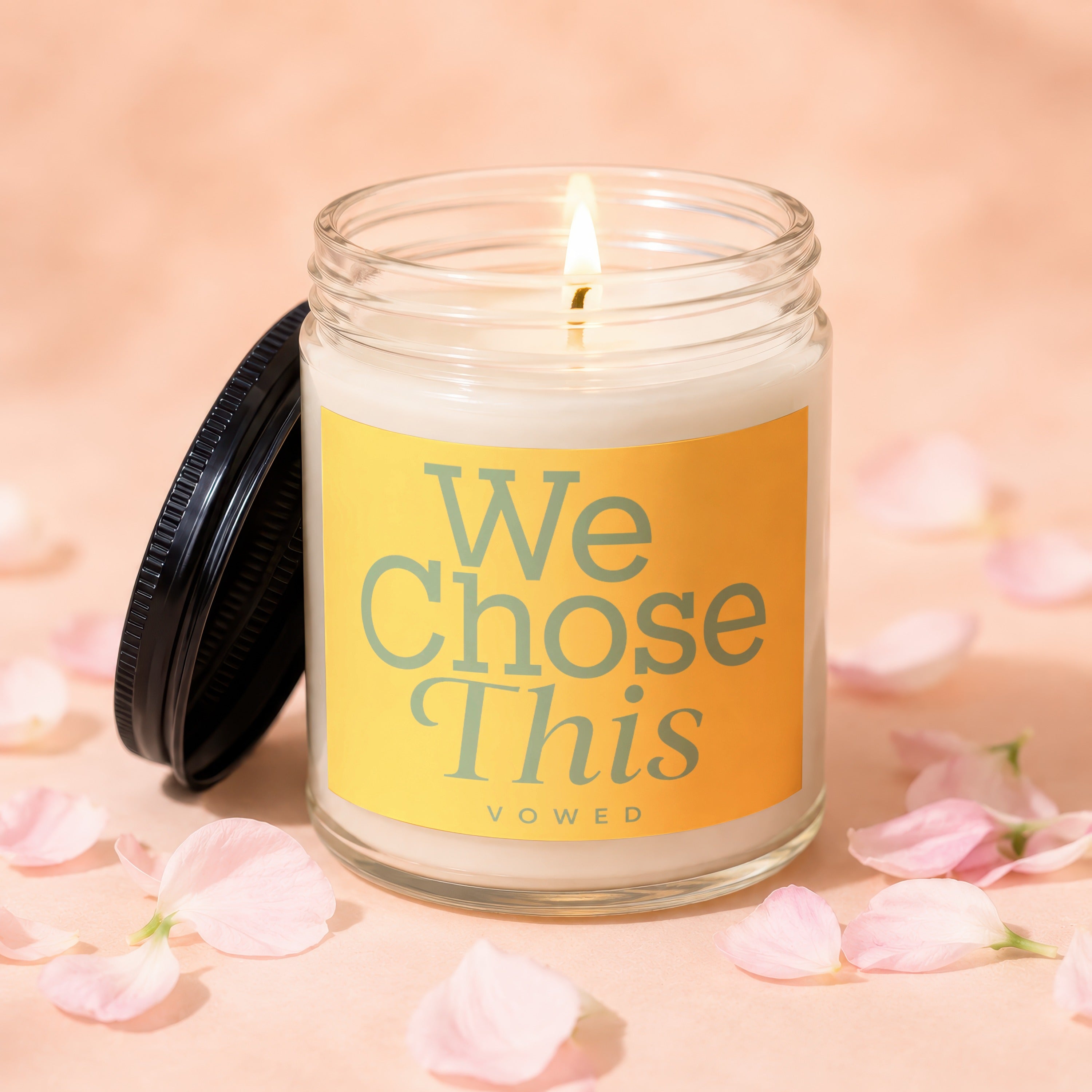 Jar candle with yellow label reading "We Chose This VOWED" surrounded by pink petals.