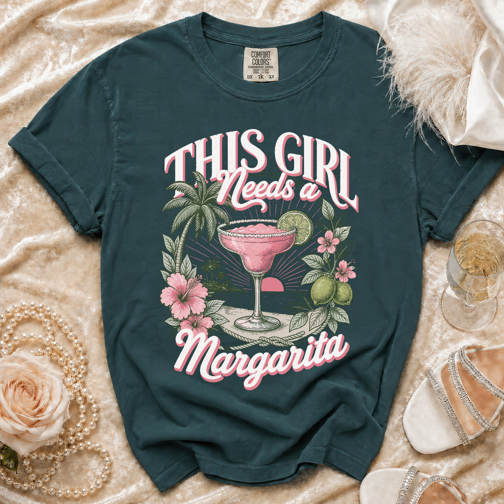 Teal t-shirt with "This Girl Needs a Margarita" graphic featuring a margarita, beach, and flowers.