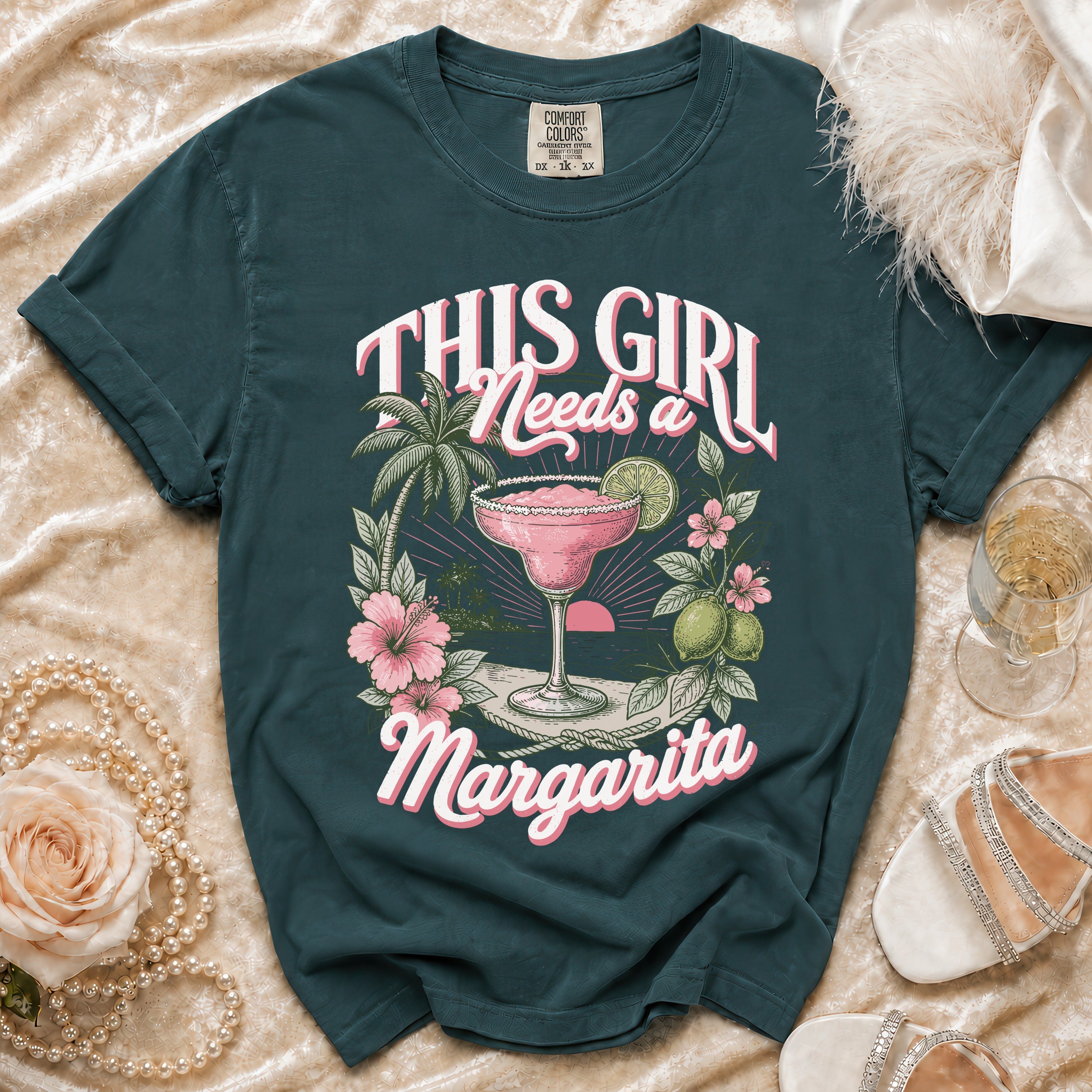Teal t-shirt with "This Girl Needs a Margarita" graphic featuring a margarita, beach, and flowers.