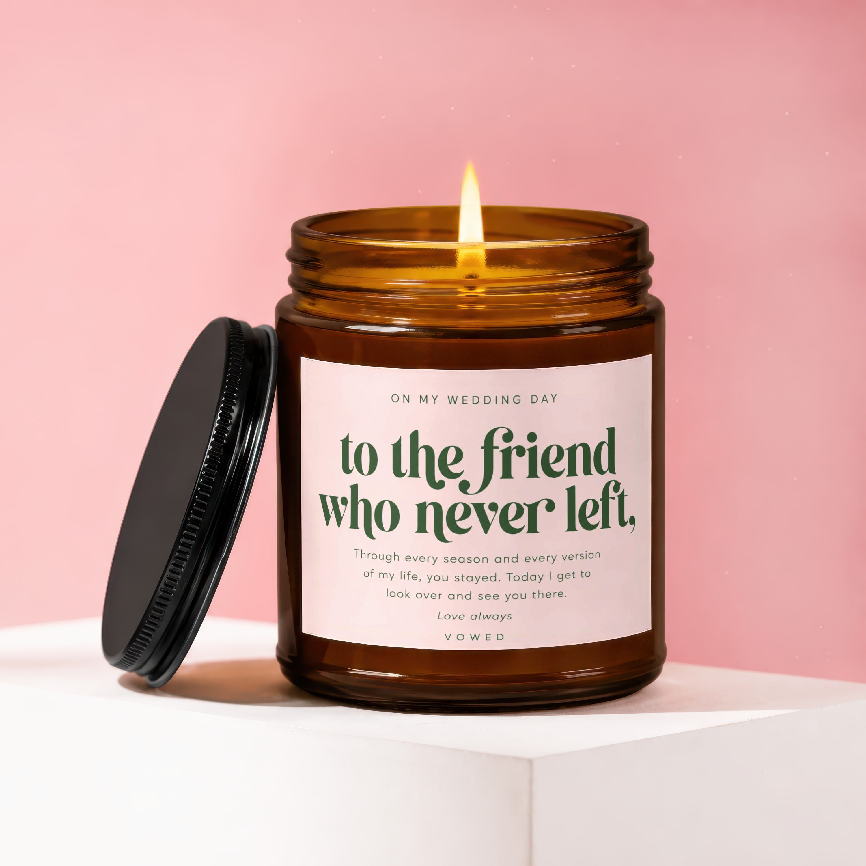 Amber candle with lit flame, pink label reads "to the friend who never left".