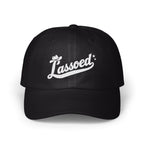 A black baseball cap with white embroidered cursive text that reads Lassoed on the front.