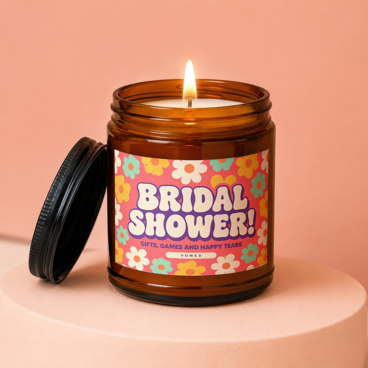 Bridal Shower candle in amber jar with floral label, lit wick and removed lid.