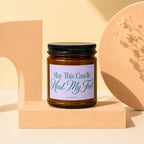 Amber glass candle with lavender label that reads "May This Candle Heal My Feet".
