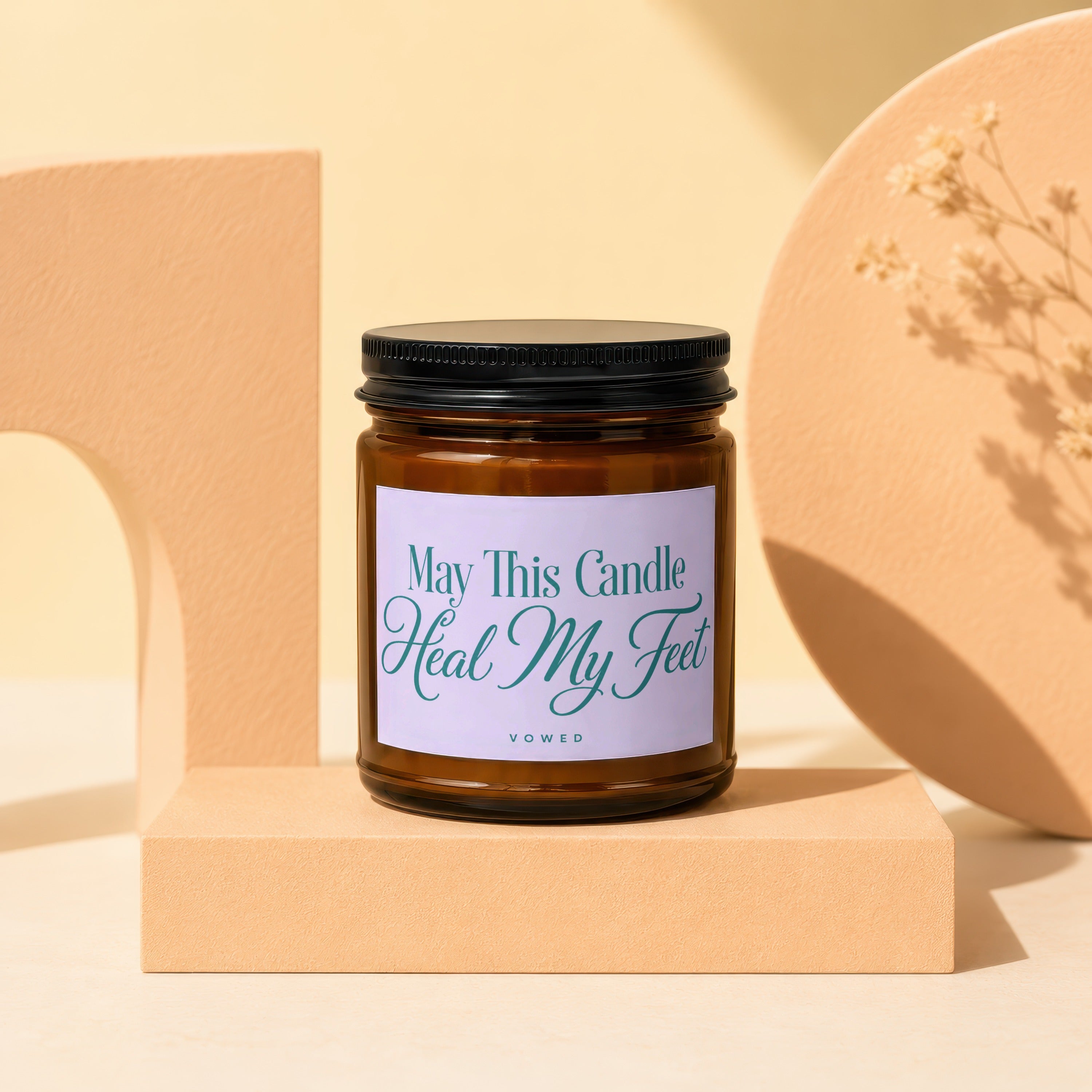 Amber glass candle with lavender label that reads "May This Candle Heal My Feet".