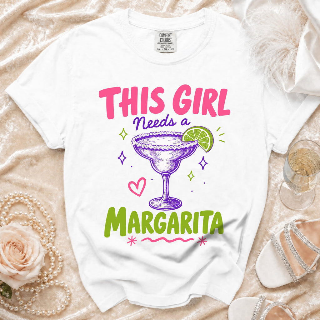 White t-shirt with pink text "THIS GIRL Needs a Margarita" and margarita graphic.
