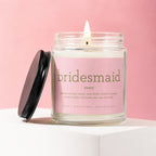 Lit candle in a jar with a pink label saying "bridesmaid noun professional hype woman, dress fluffer, timeline manager, emotion holder, and bride's day-one ride or die."
