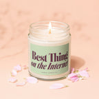 Candle with "Best Thing on the Internet" text, lit flame, and pink petals.