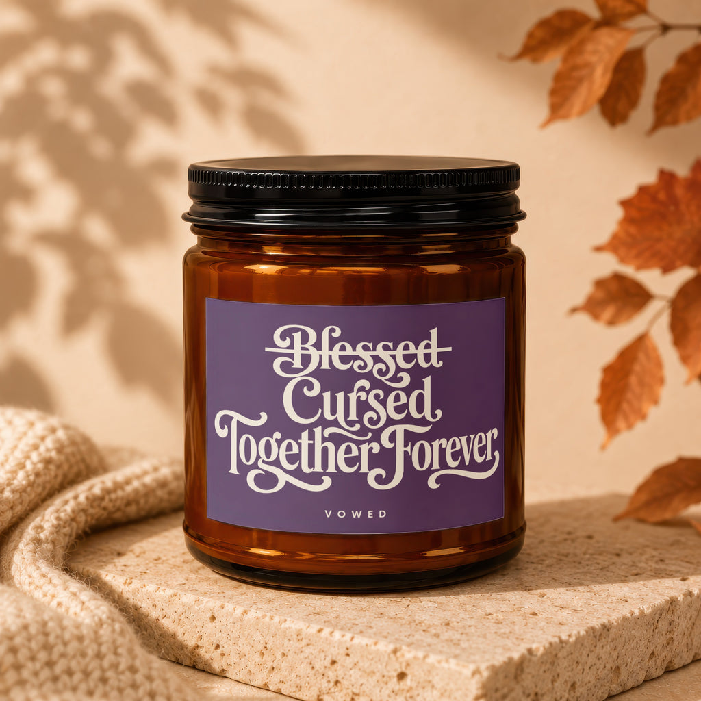 Brown glass candle with purple label reading "Blessed Cursed Together Forever VOWED".