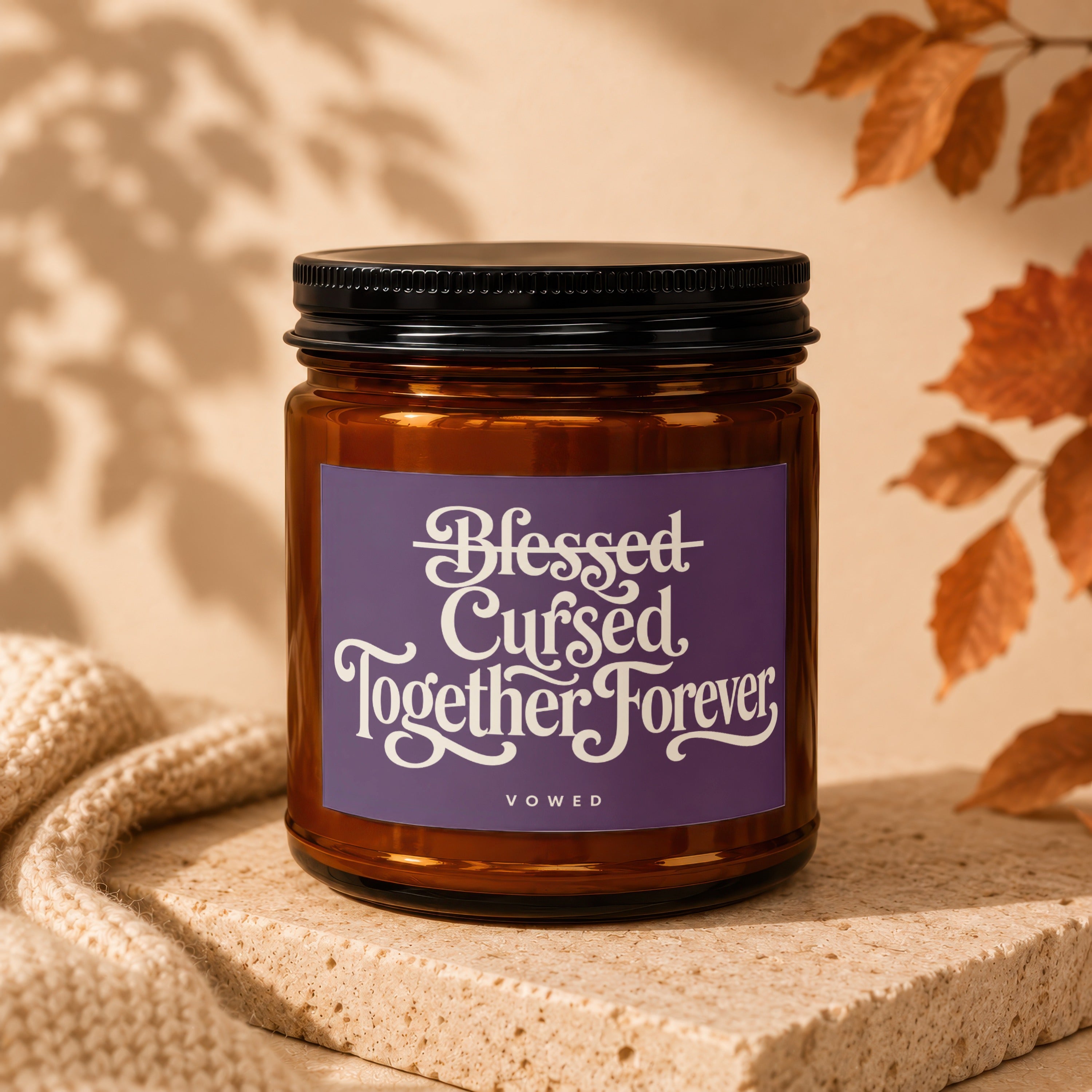 Brown glass candle with purple label reading "Blessed Cursed Together Forever VOWED".
