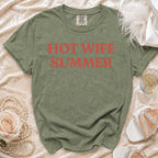 Green t-shirt with "Hot Wife Summer" text, pearls, rose, champagne, and shoes.