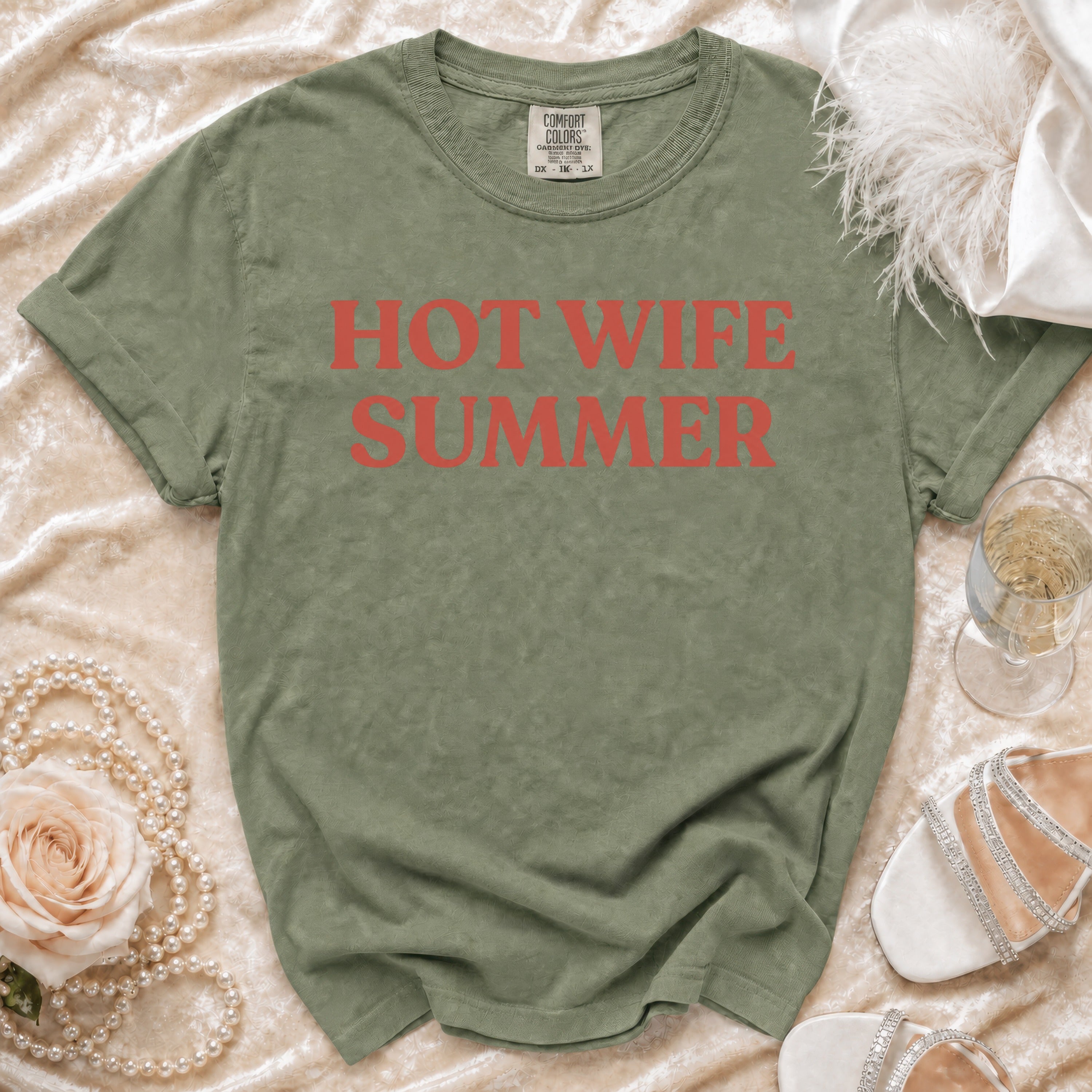 Green t-shirt with "Hot Wife Summer" text, pearls, rose, champagne, and shoes.