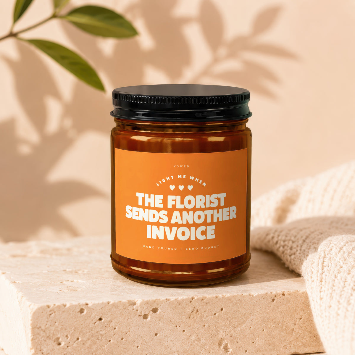 Candle with orange label: "Light me when the florist sends another invoice."
