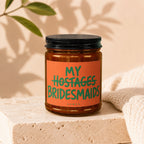 Candle labeled "MY HOSTAGES BRIDESMAIDS" with "VOWED" below, on a stone block.