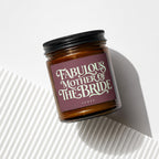 Brown candle in glass jar with "Fabulous Mother of The Bride" text on a plum label.