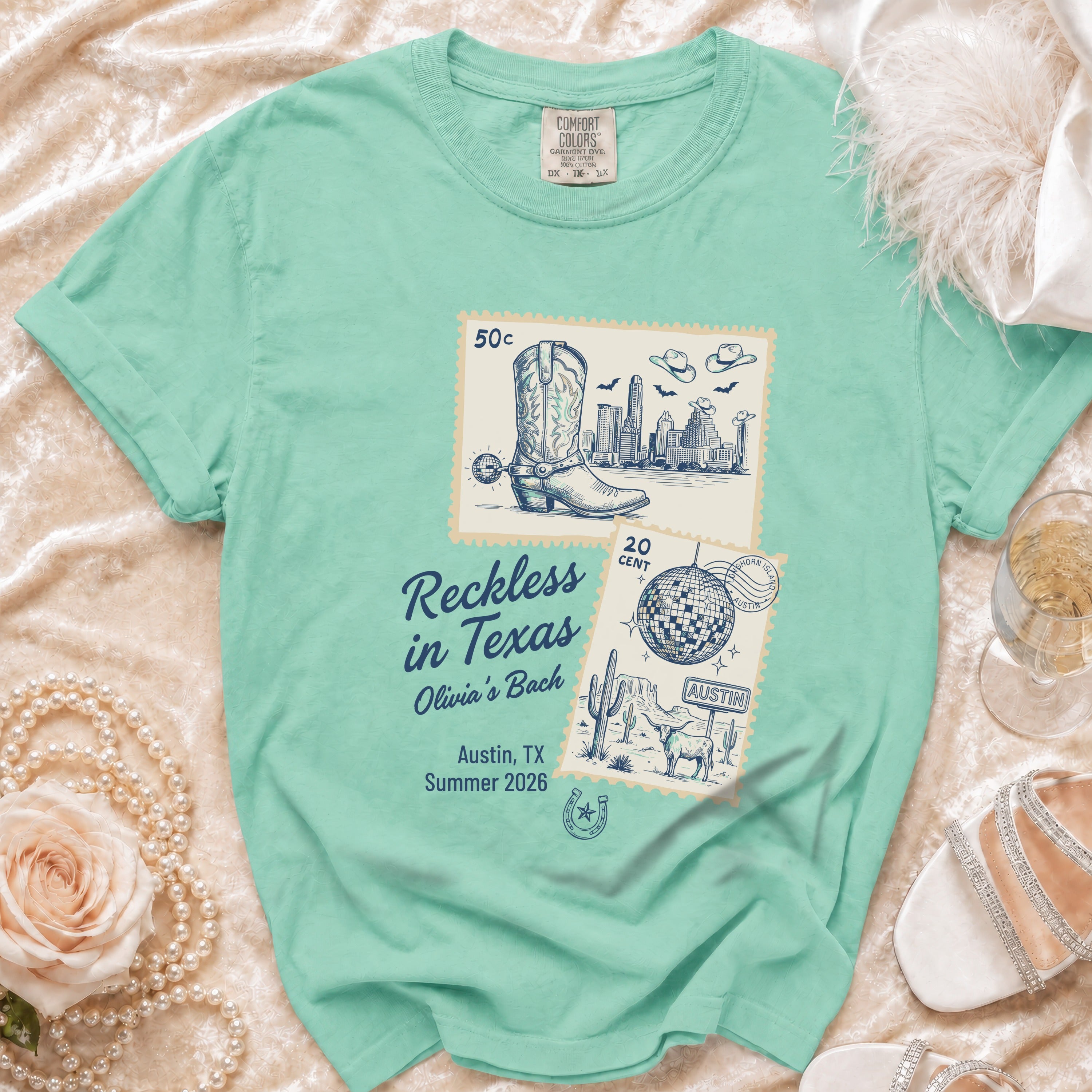 T-shirt with vintage stamps showing a cityscape and cowboy boots, reads "Reckless in Texas Olivia's Bach".