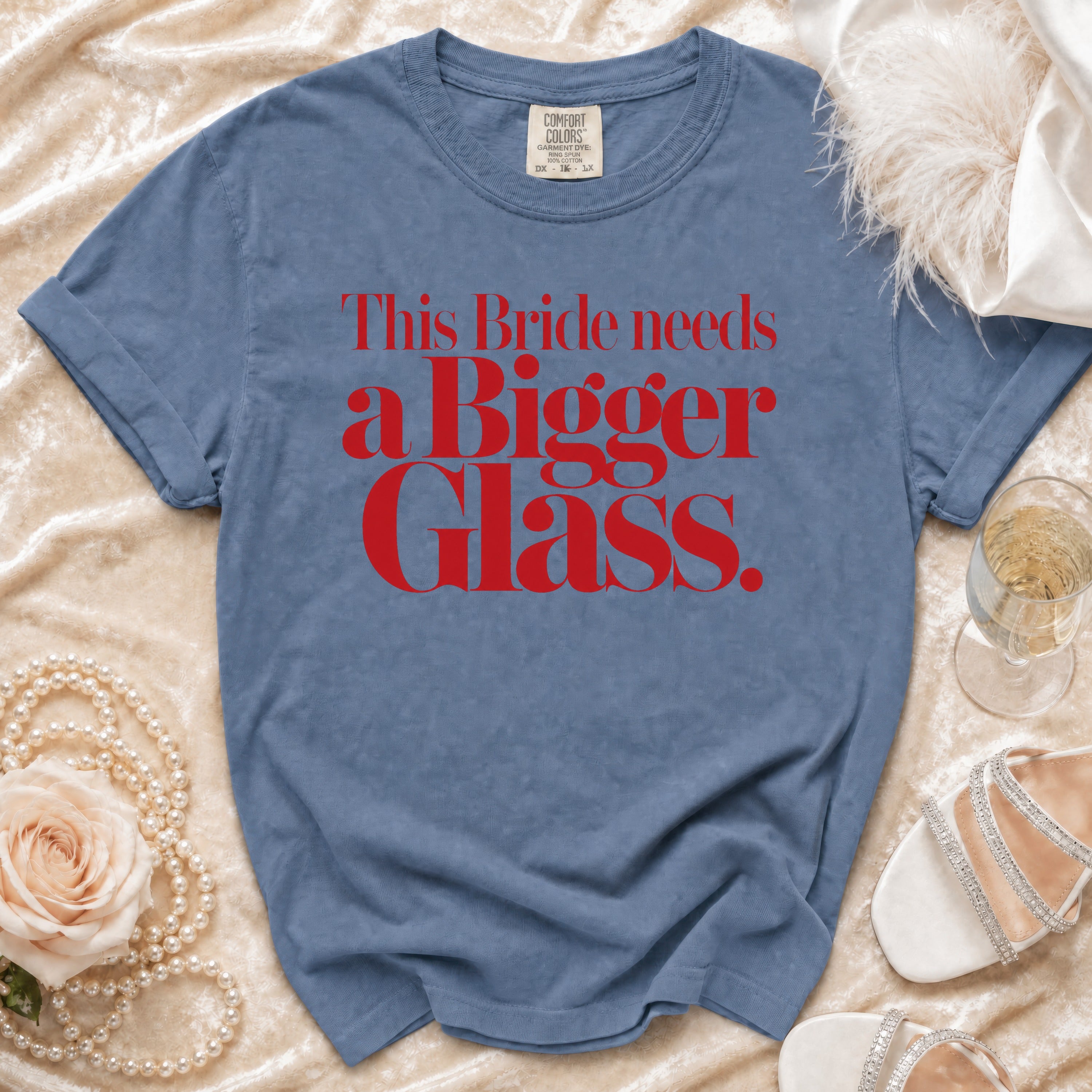Blue t-shirt with red text reading "This Bride needs a Bigger Glass."