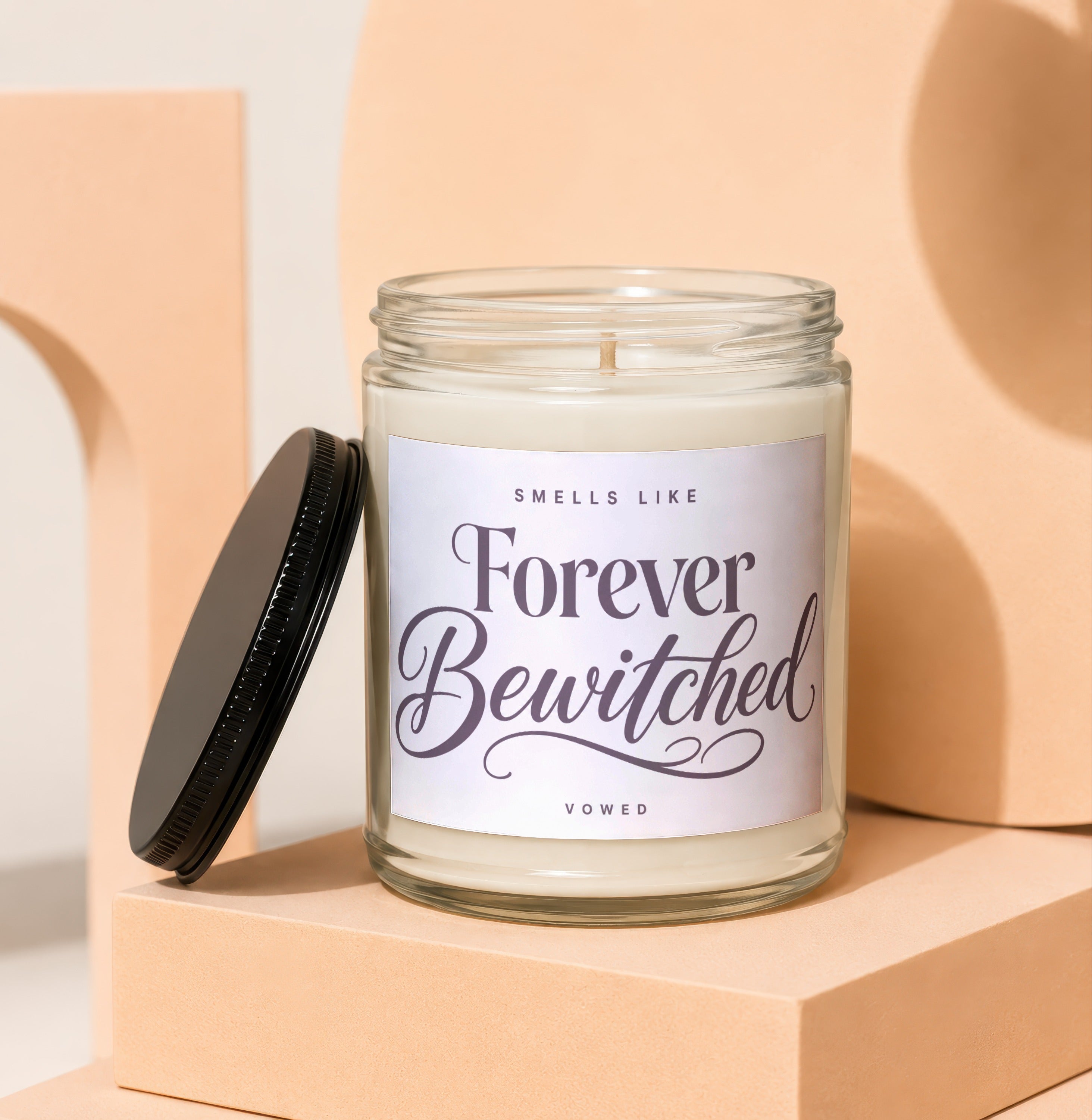 Glass candle with a black lid and label that reads "Smells Like Forever Bewitched".