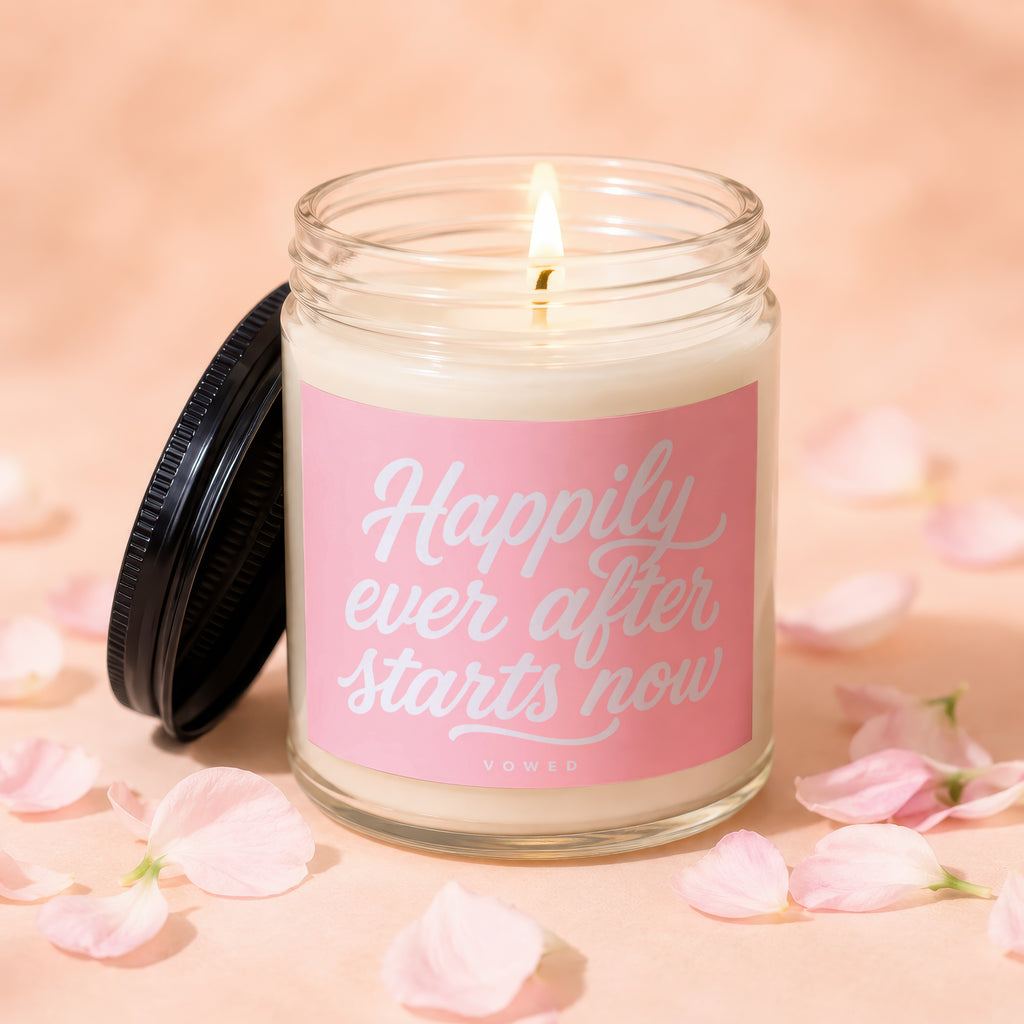 Lit candle in glass jar with pink label reading "Happily ever after starts now."