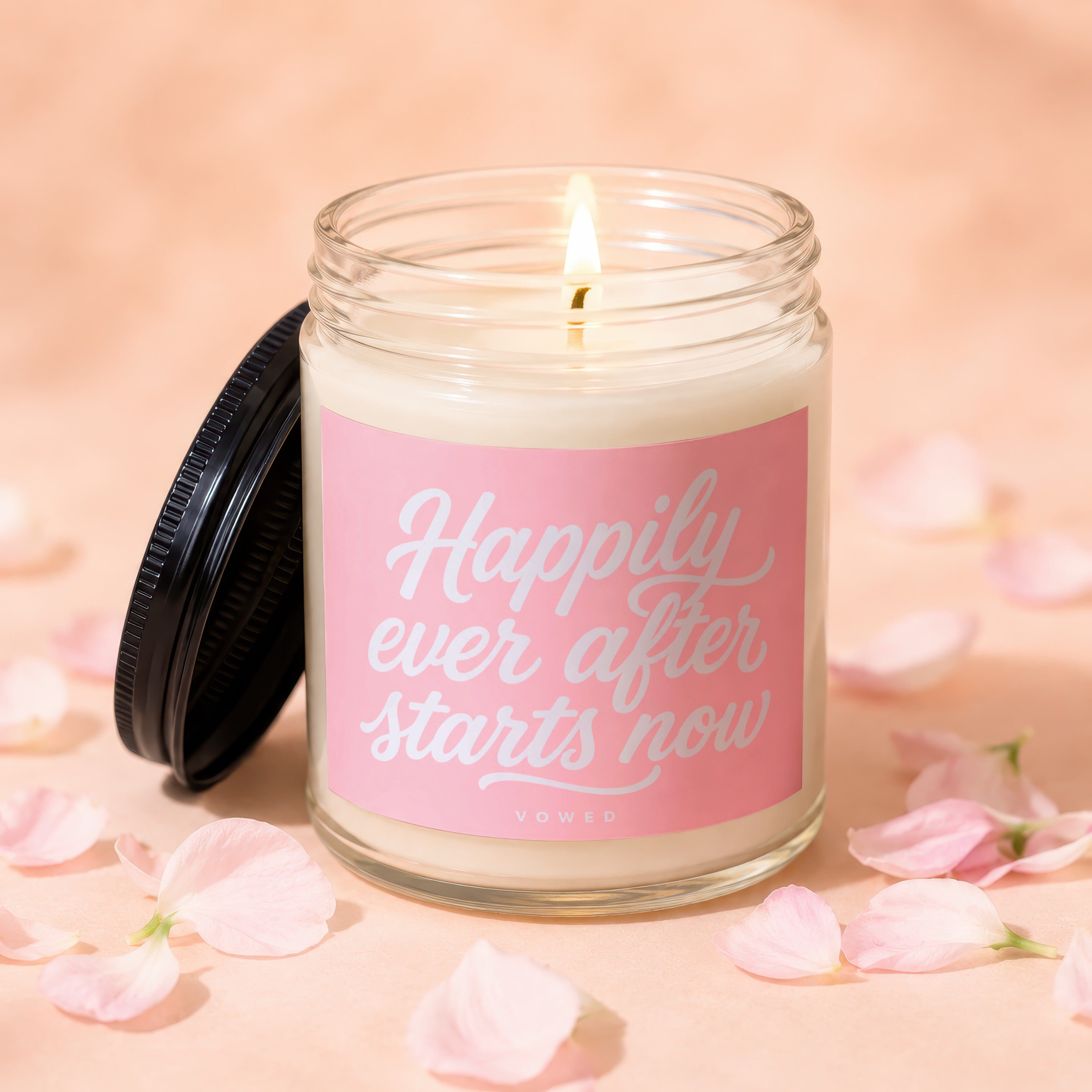 Lit candle in glass jar with pink label reading "Happily ever after starts now."