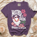 Purple t-shirt with "Mother of the Bride Spooky & Proud" text and ghost graphic.