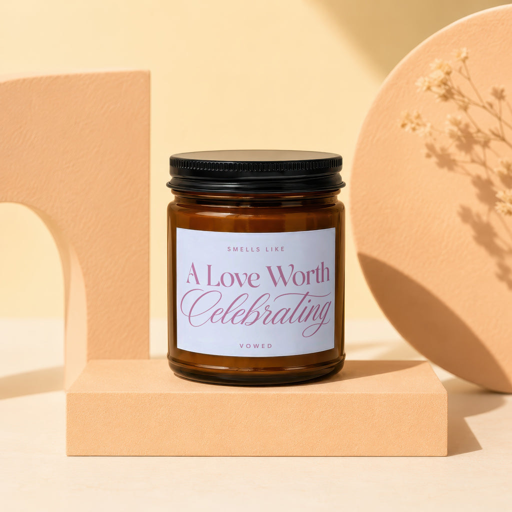 Candle in amber jar with "A Love Worth Celebrating VOWED" label.