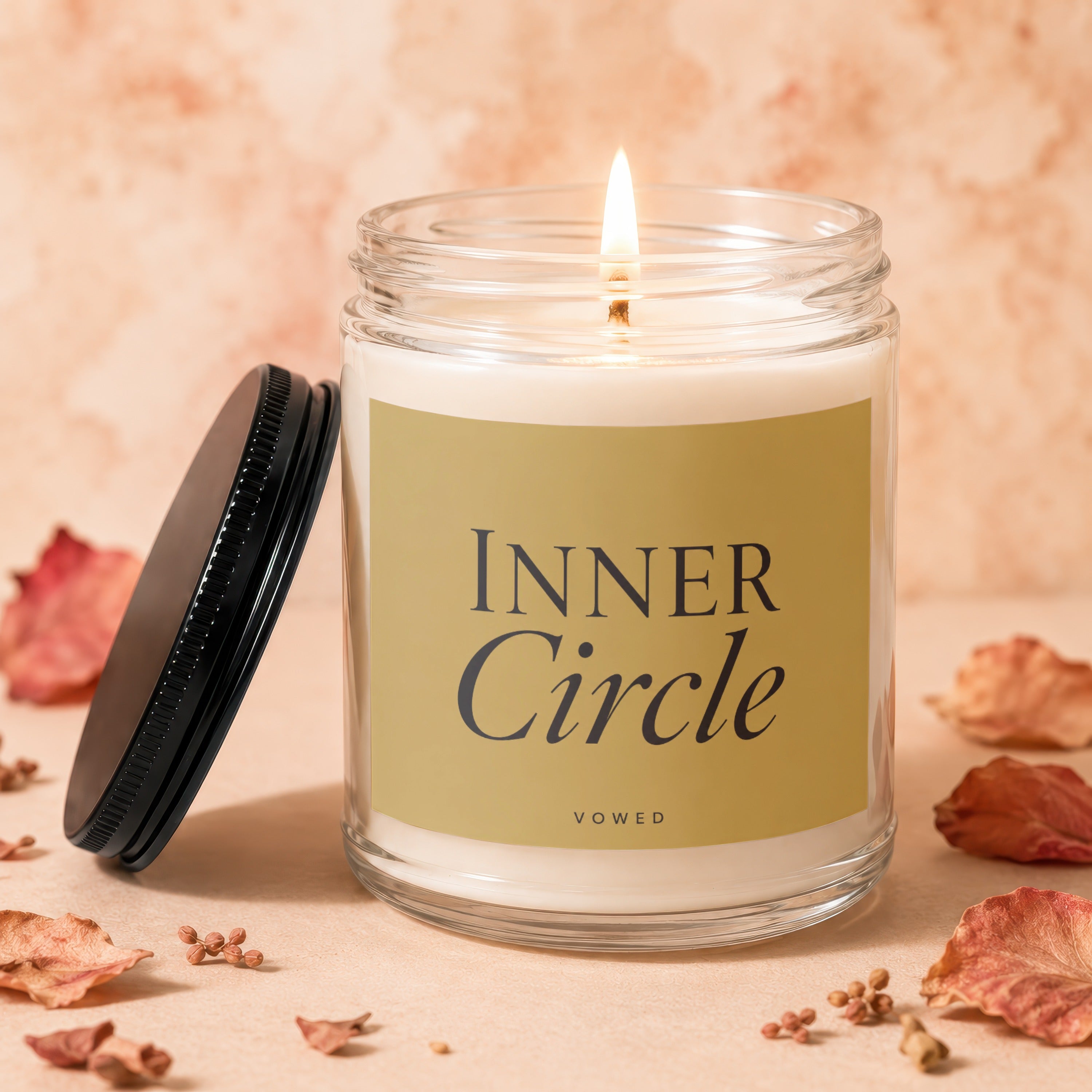 Candle with lit wick and gold label reading "Inner Circle" "Vowed".
