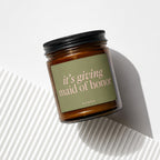 Amber glass candle with "it's giving maid of honor" text on a green label.