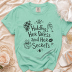 Mint green t-shirt with black graphic text "Holding HER DRESS and HER Secrets".